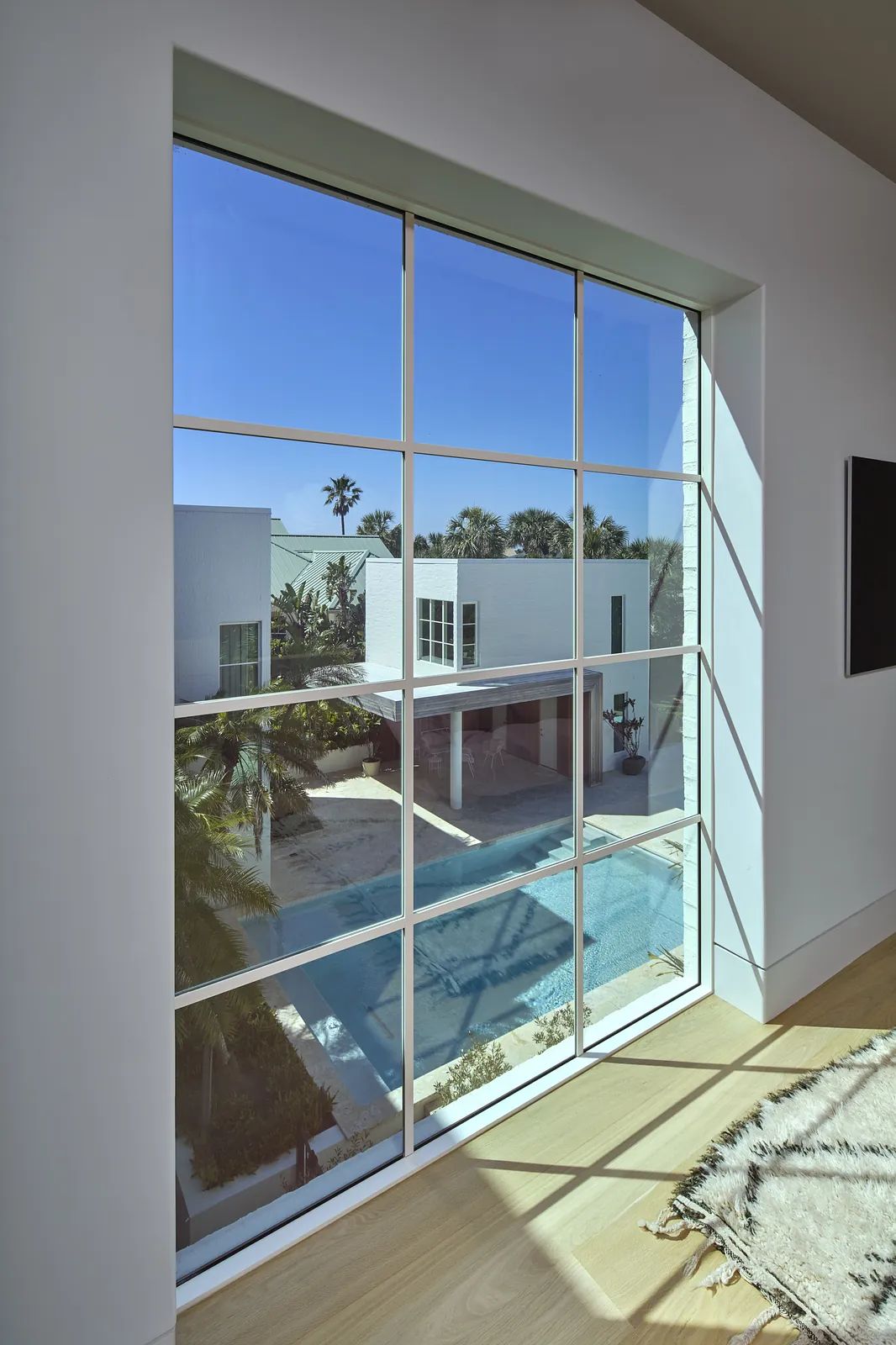 Large window with grid design showing pool area and greenery outside.