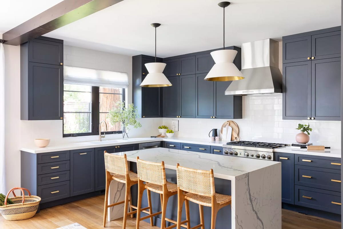 Kitchen with blue cabinets, white countertop, large island, bar stools, and stainless steel appliances