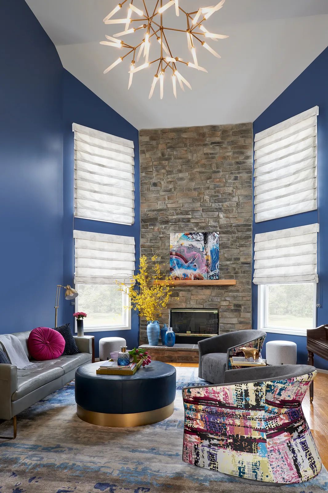 Living room with gray sofa, blue coffee table, colorful chair, area rug, and stone fireplace.