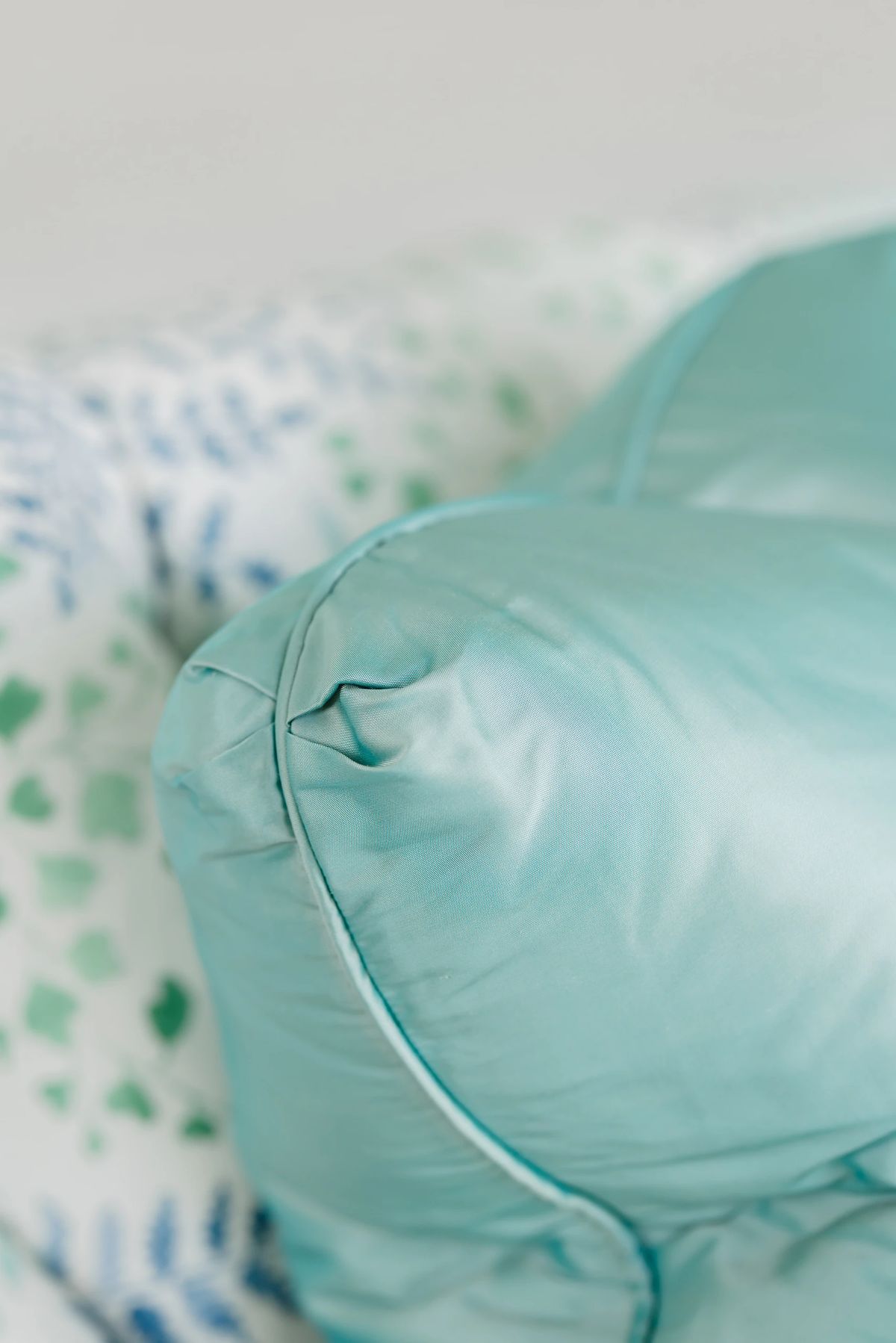 Close-up of a teal pillow against a patterned background.