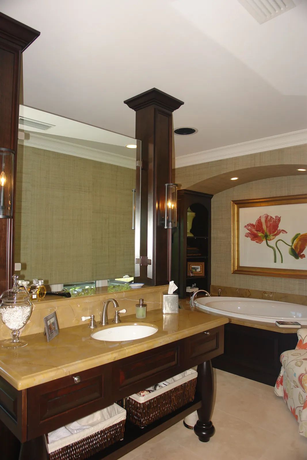 Bathroom with dark wood vanity, beige countertop, dual sinks, framed flower painting, and white bathtub.
