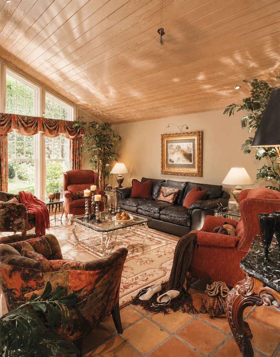 Living room with black leather sofa, red armchairs, glass coffee table, area rug, and large windows.