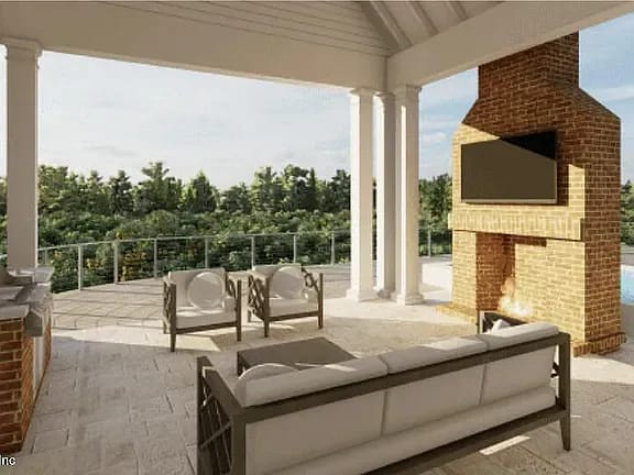 Outdoor deck with sofa, armchairs, coffee table, brick fireplace, and built-in grill.