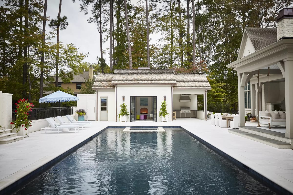Outdoor space with swimming pool, lounge chairs, pavilion, and greenery.