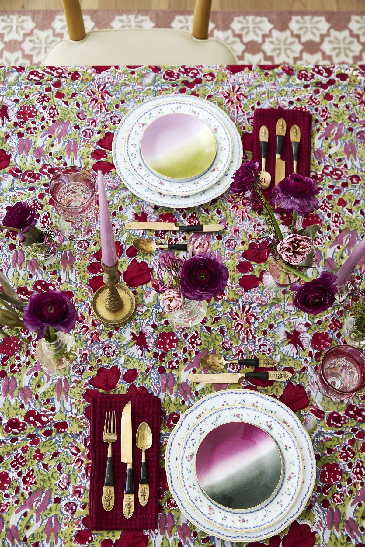 Dining room table with floral tablecloth, plates, utensils, glasses, and floral centerpieces