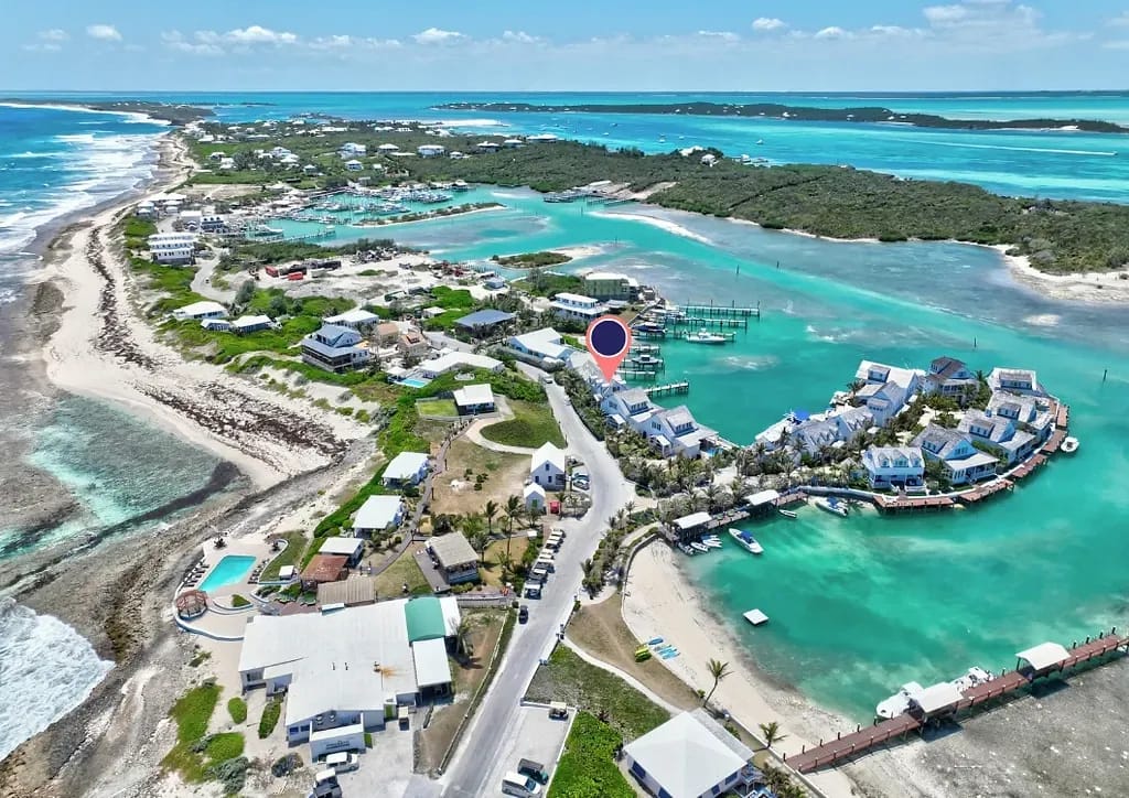 Aerial view of a coastal area with residential buildings, marina, beaches, and turquoise waters.
