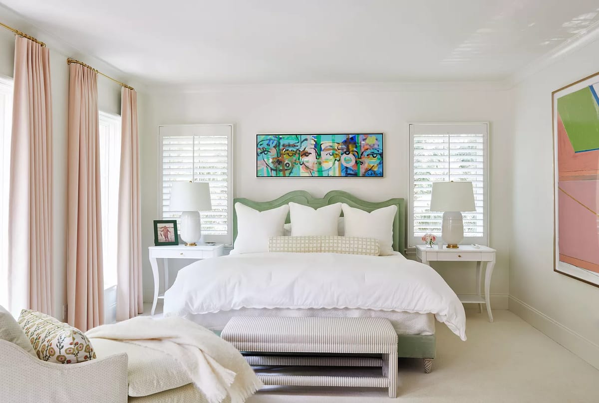 Bedroom with green headboard bed, white bedding, nightstands, lamps, and patterned armchair