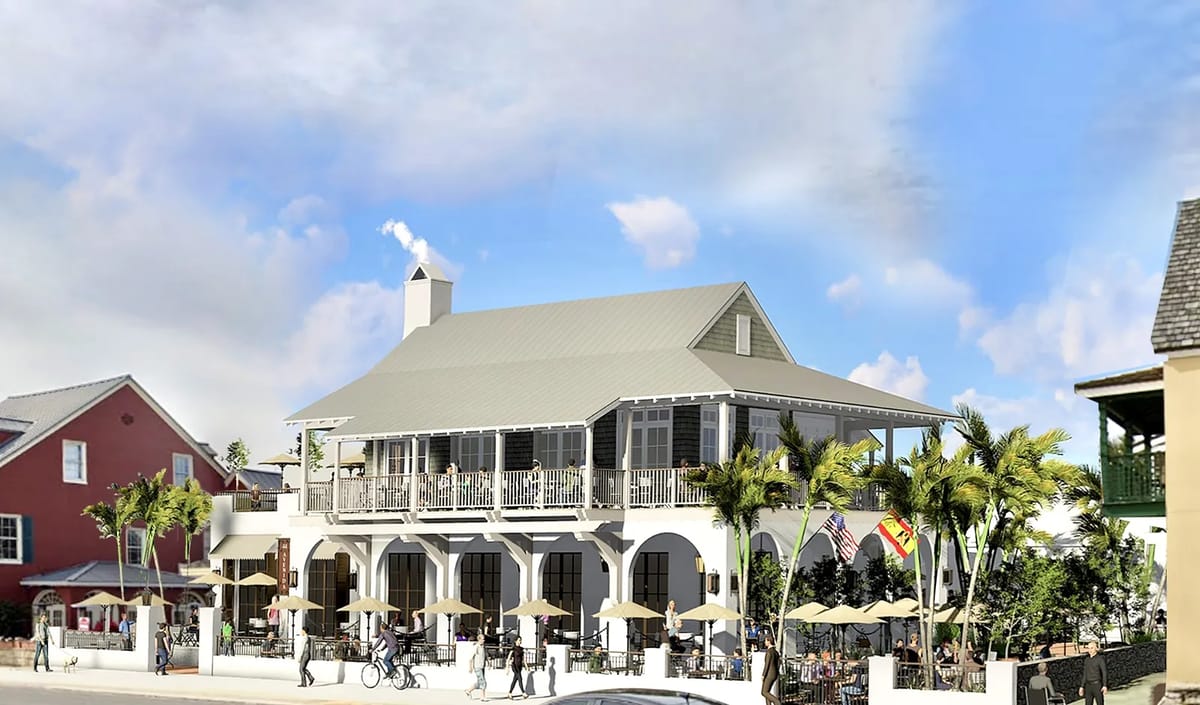 Exterior view of a two-story building with gray metal roof, columns, wraparound porch, and outdoor seating.