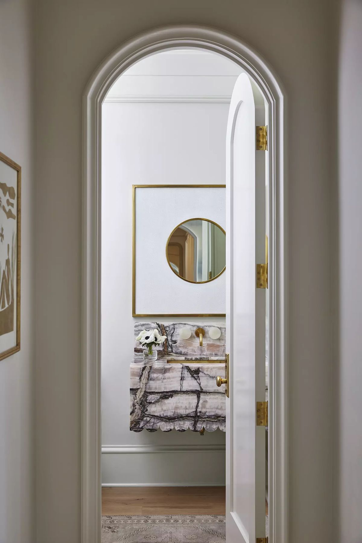 Powder room with white door, oval mirror, marble countertop, and textured rug.