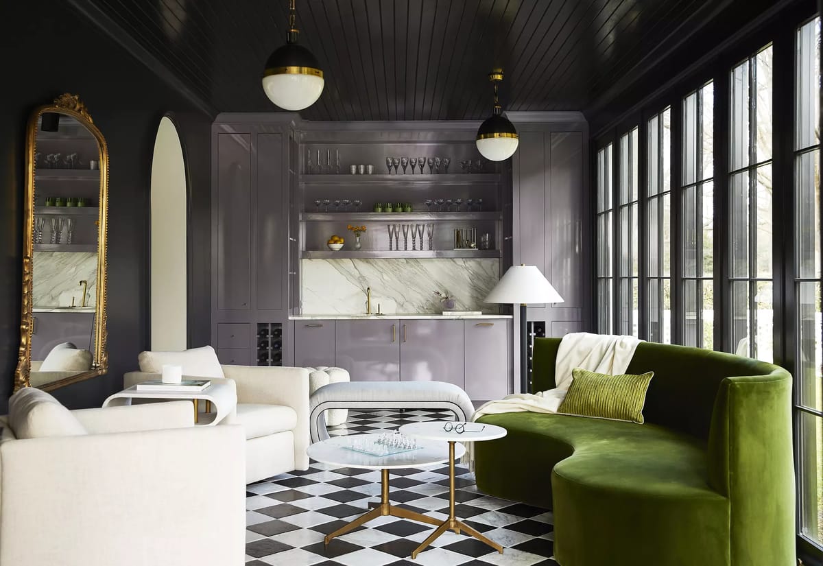 Living room with green curved sofa, white rounded sofa, glass coffee table, large mirror, and checkered flooring