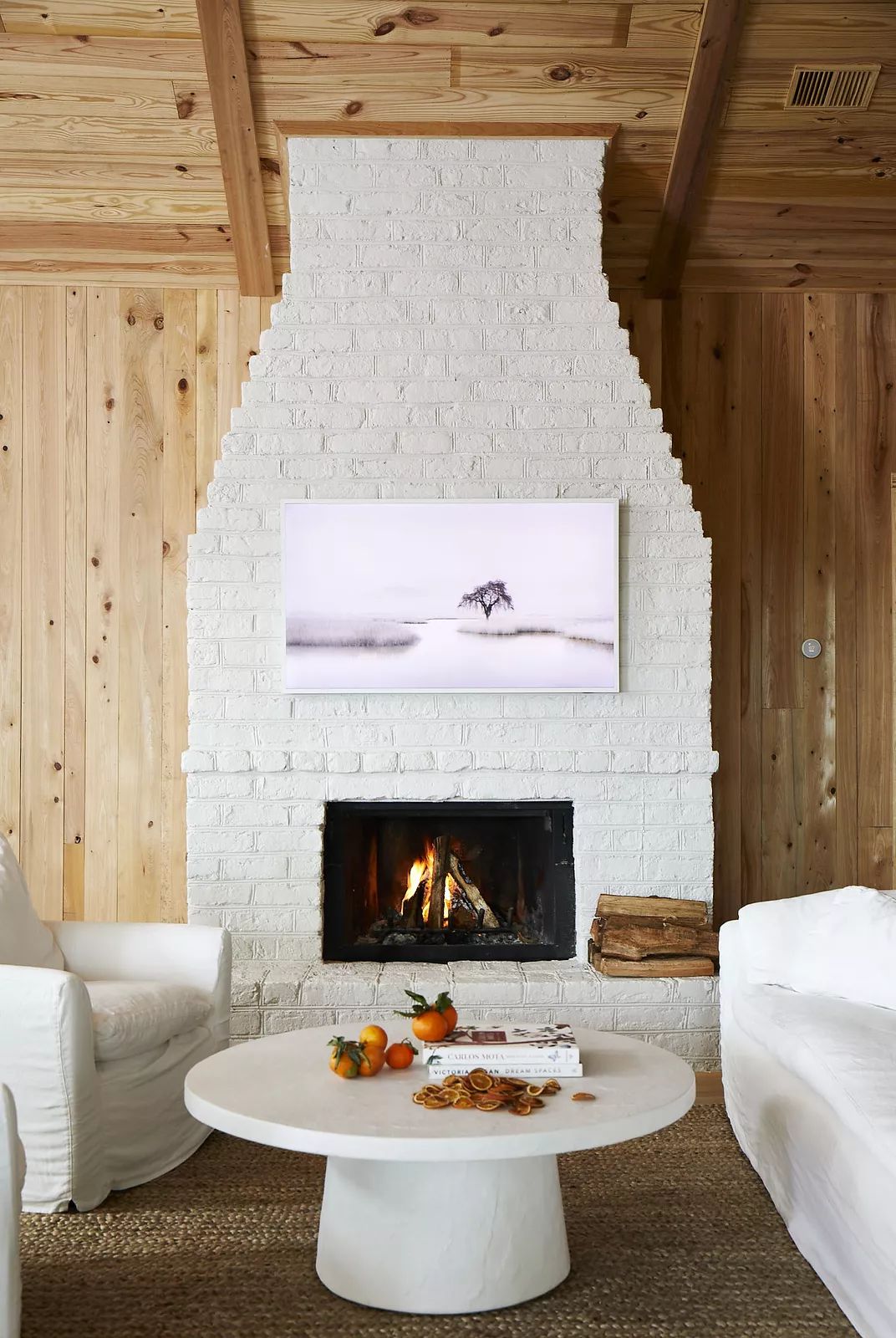 Living room with white brick fireplace, armchairs, round coffee table, and woven rug.