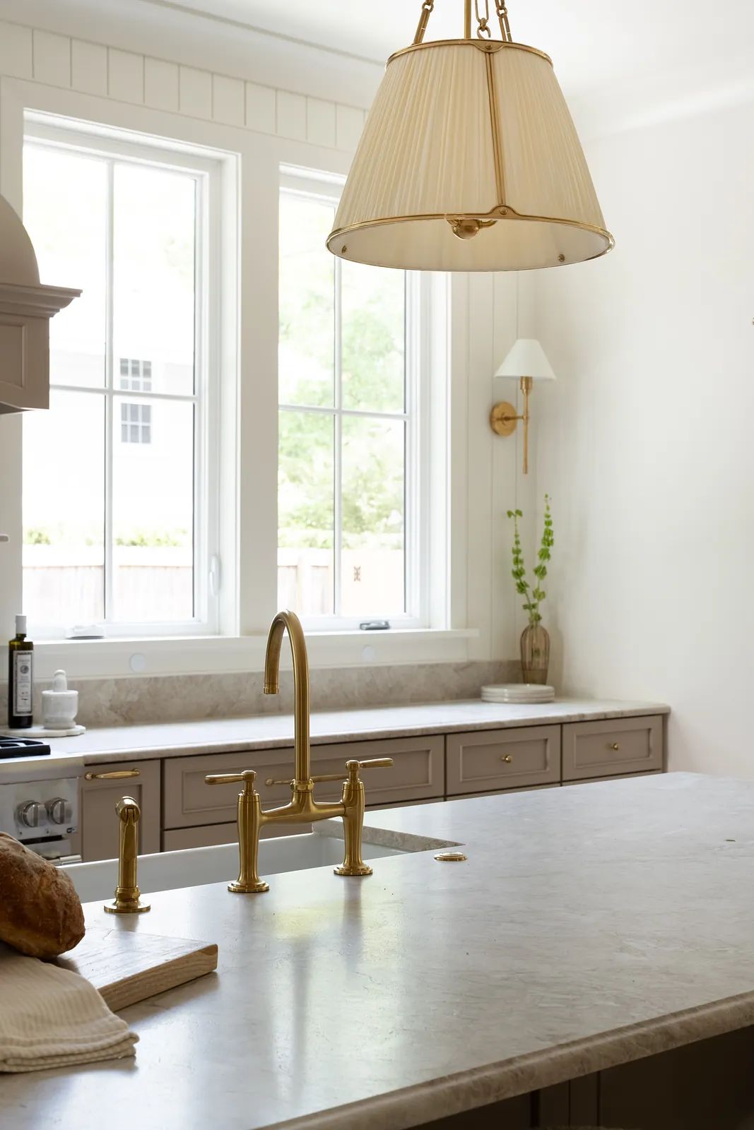 Kitchen with central island, stone countertop, brass faucet, cabinetry, and natural light from large windows