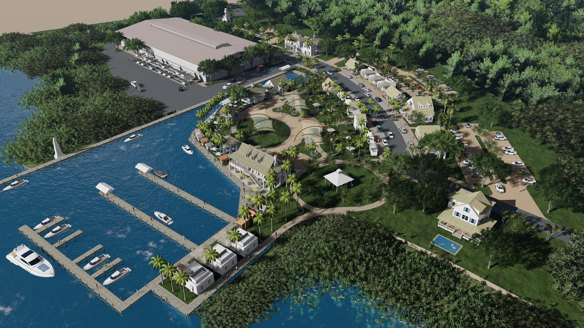 Aerial view of waterfront development with marina, buildings, pathways, and greenery.