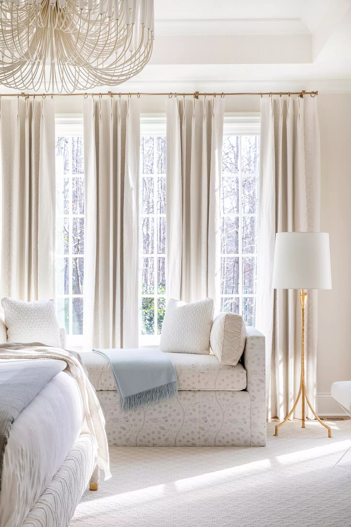 Bedroom with upholstered bed, daybed, large windows, sheer curtains, and floor lamp.