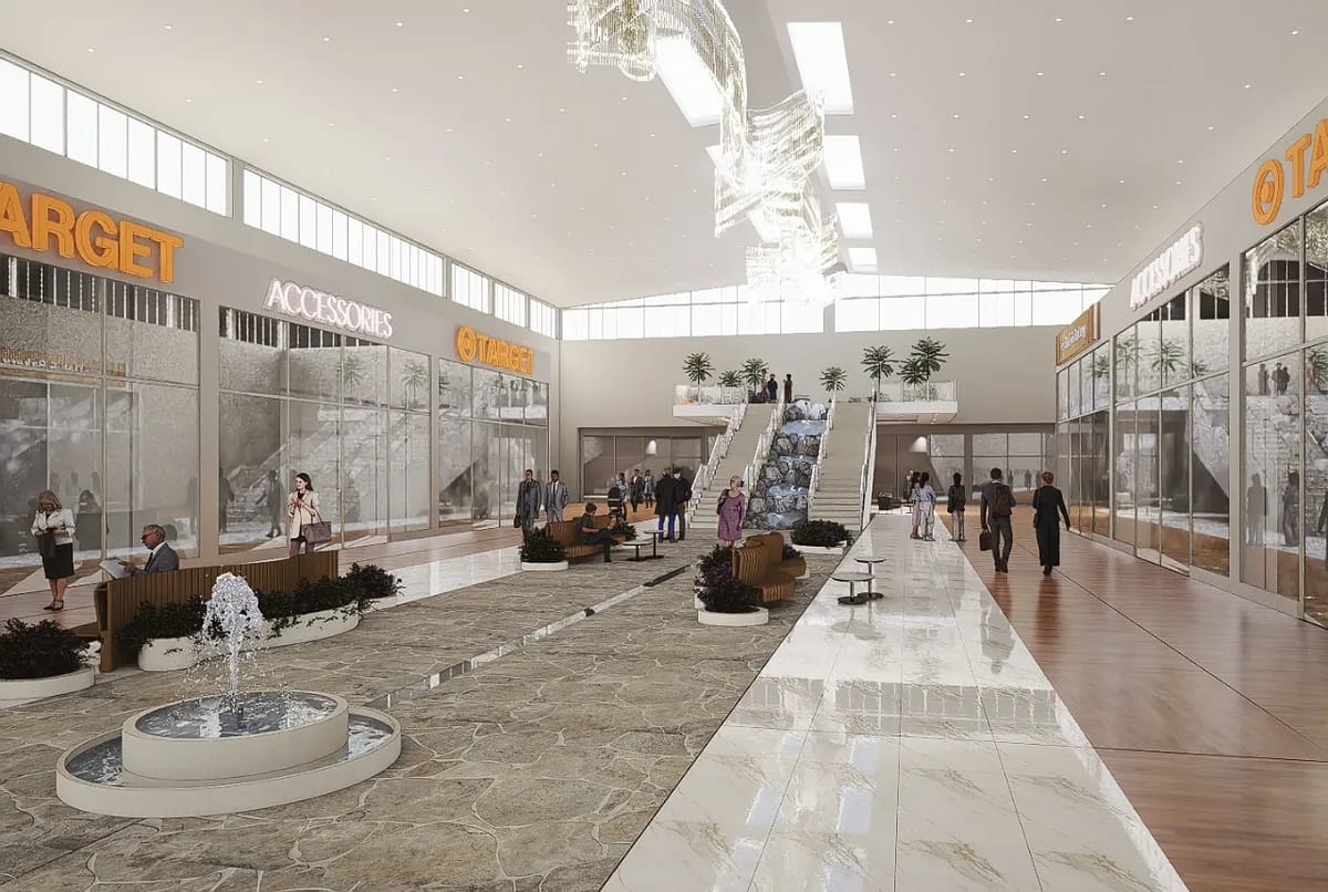 Indoor shopping center with water fountain, seating areas, glass storefronts, and large windows.