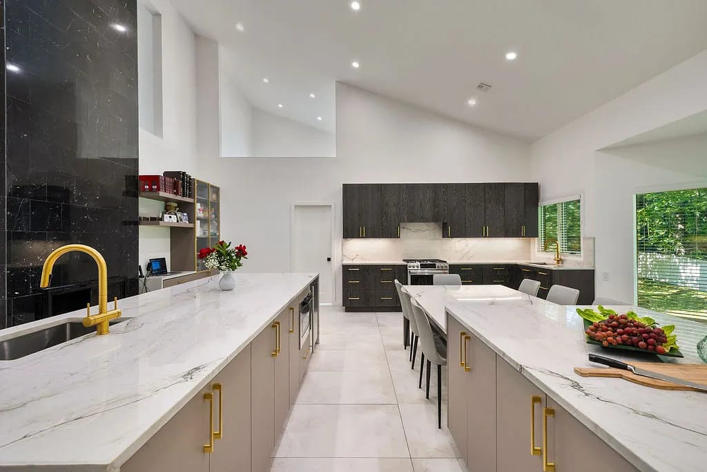 Kitchen with marble island, beige cabinets, dark wood cabinetry, stove, dining table, and natural light from windows.