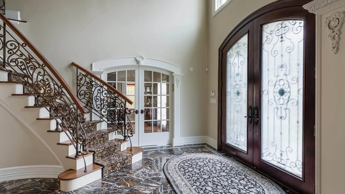 Foyer with wrought iron staircase, double entry doors, marble flooring, and decorative area rug