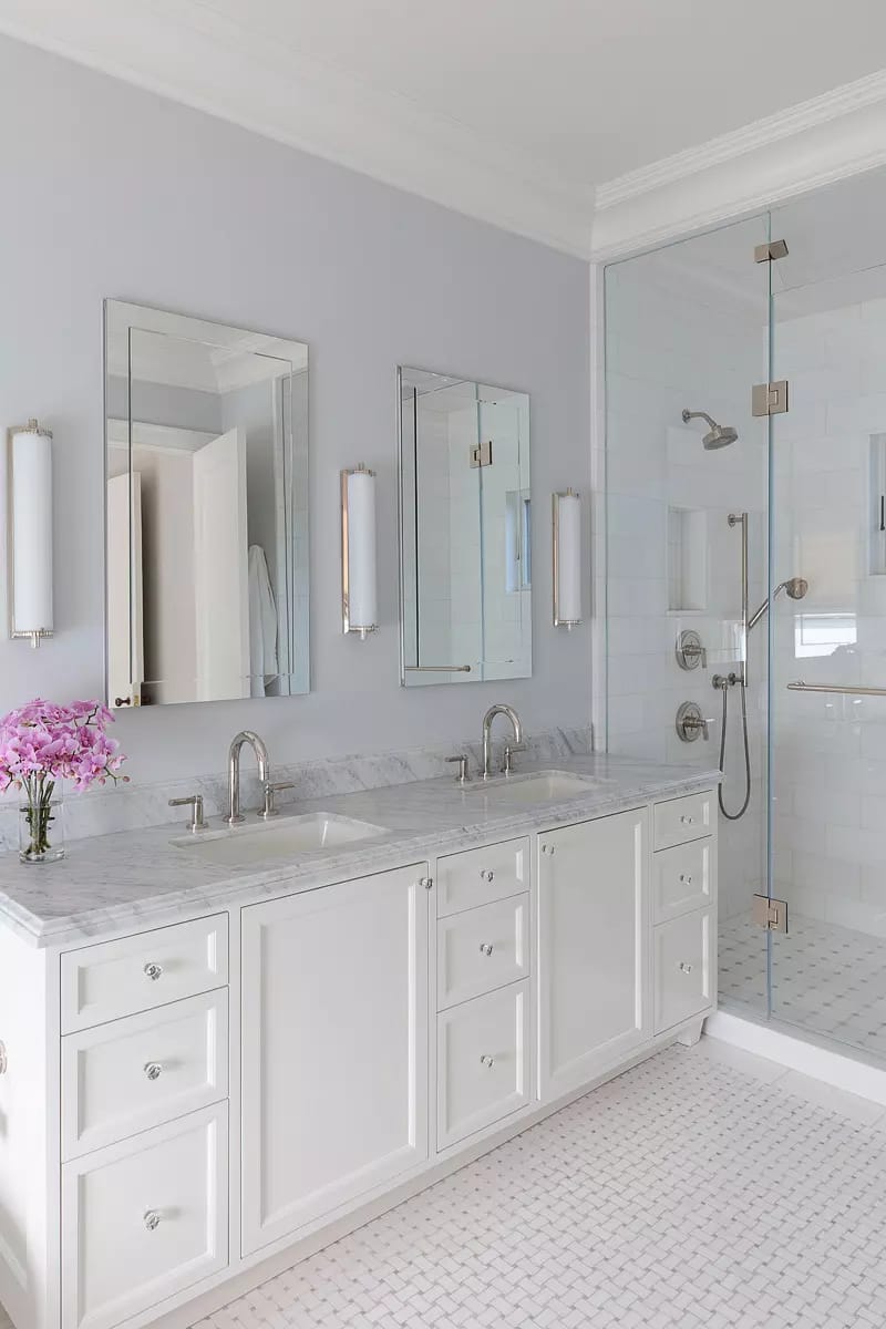 Bathroom with double vanity, marble countertop, mirrors, glass shower, and hexagonal tile flooring