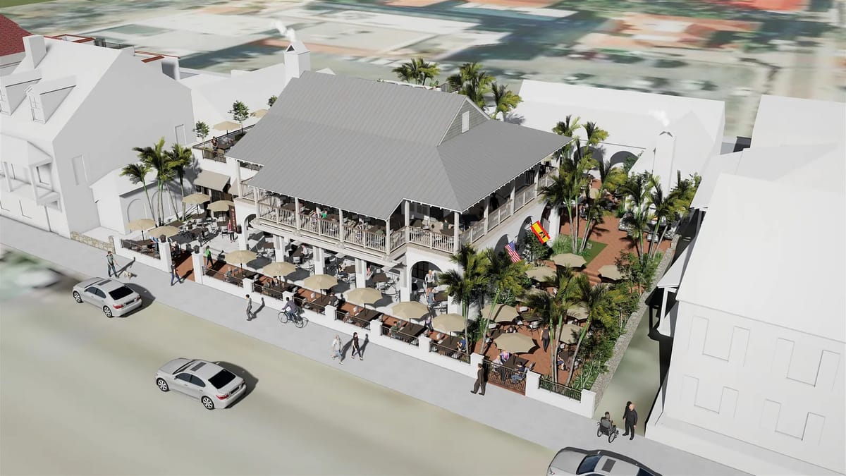 Exterior view of a two-story building with balcony, tables, umbrellas, and palm tree landscaping.