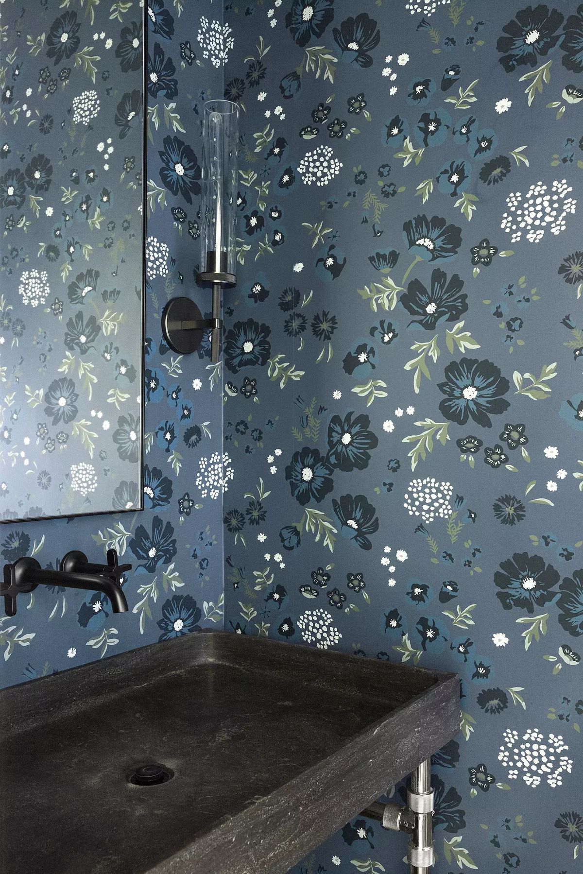 Bathroom with dark stone sink, wall-mounted faucet, and blue floral wallpaper