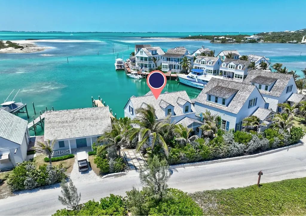 Waterfront view with coastal houses, greenery, and a boat dock.