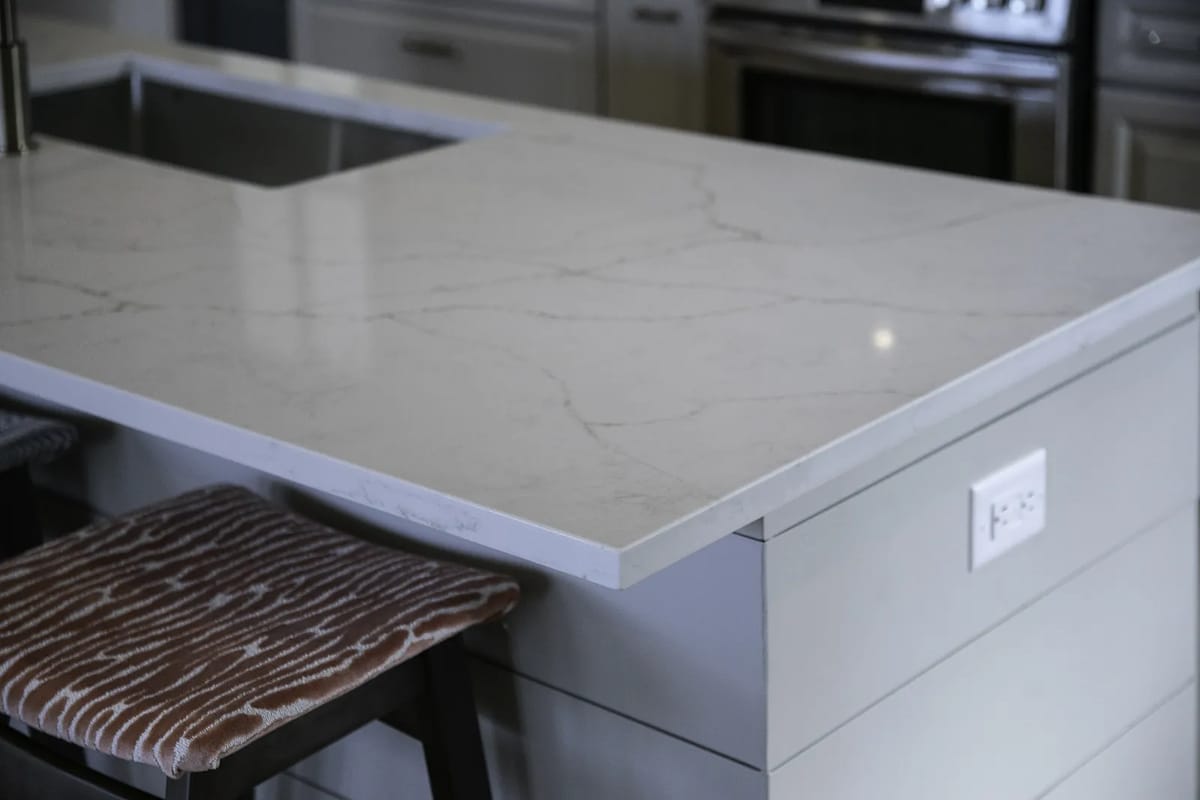 Kitchen with stone countertop, undermount sink, wooden stool, and stainless steel appliances