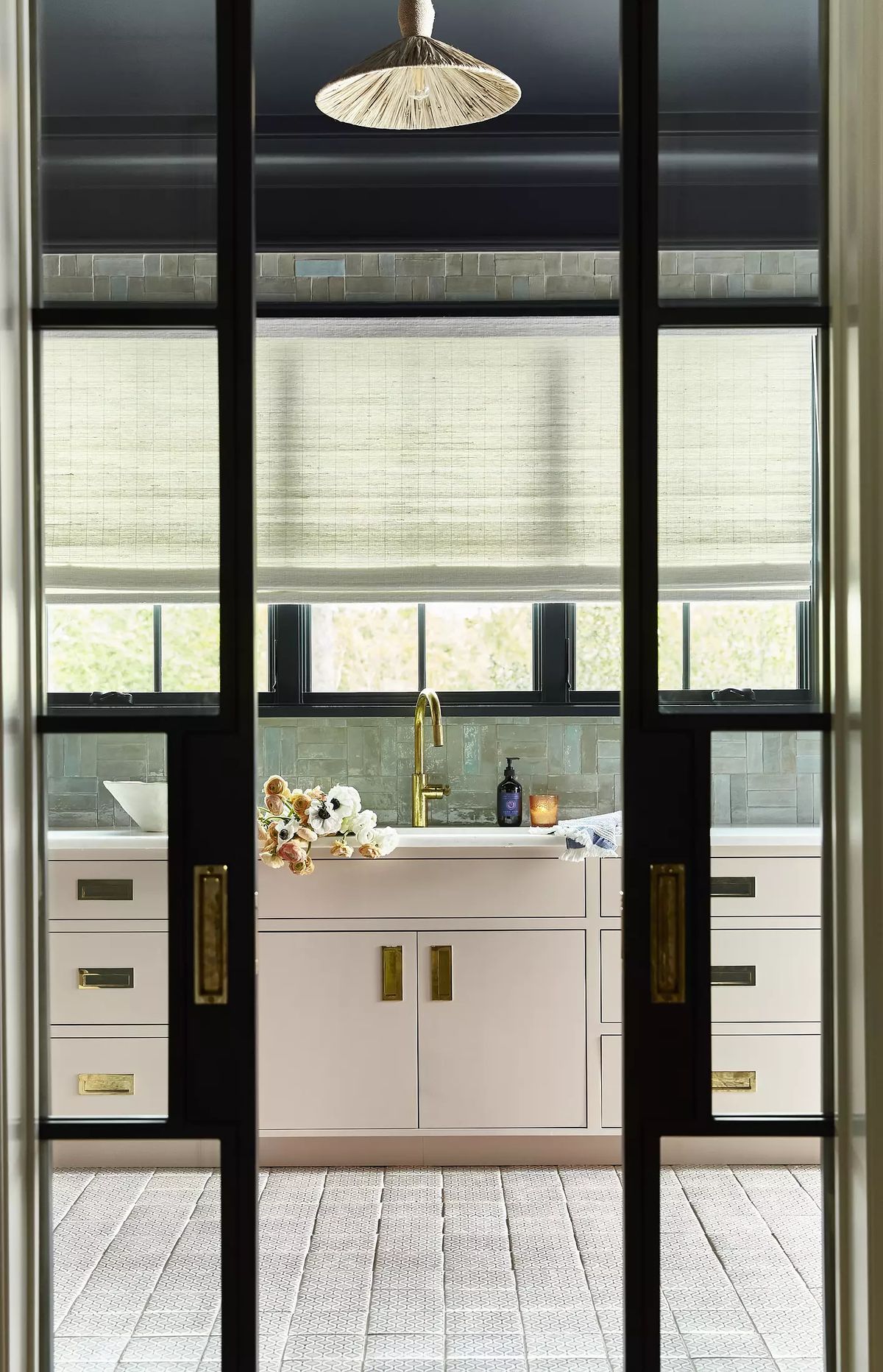 Kitchen with light cabinetry, sink, floral arrangement, tile backsplash, and decorative ceiling fixture.