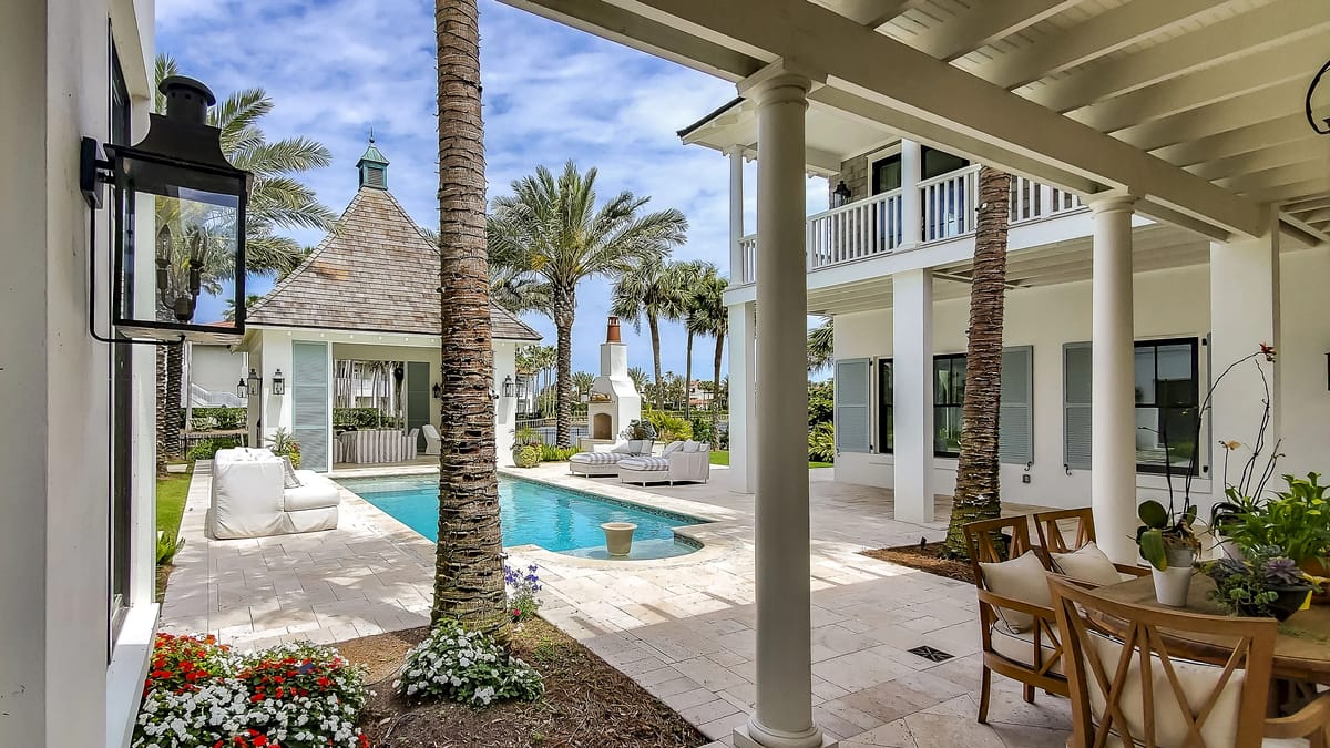 Exterior rear with swimming pool, gazebo, palm trees, lounge chairs, and dining table