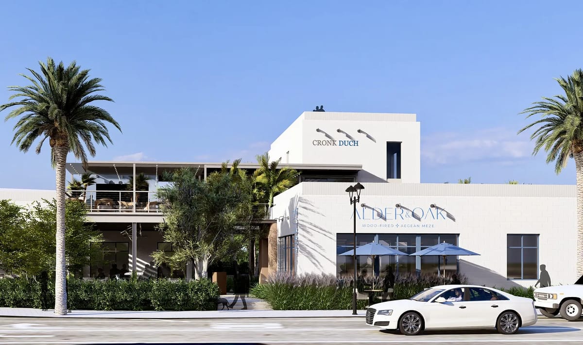 Exterior front of a building with a white facade, palm trees, patio seating, and an entrance awning.