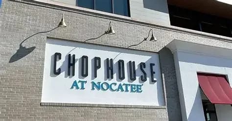 Exterior front of Chophouse at Nocatee with large sign, light fixtures, and red awning.