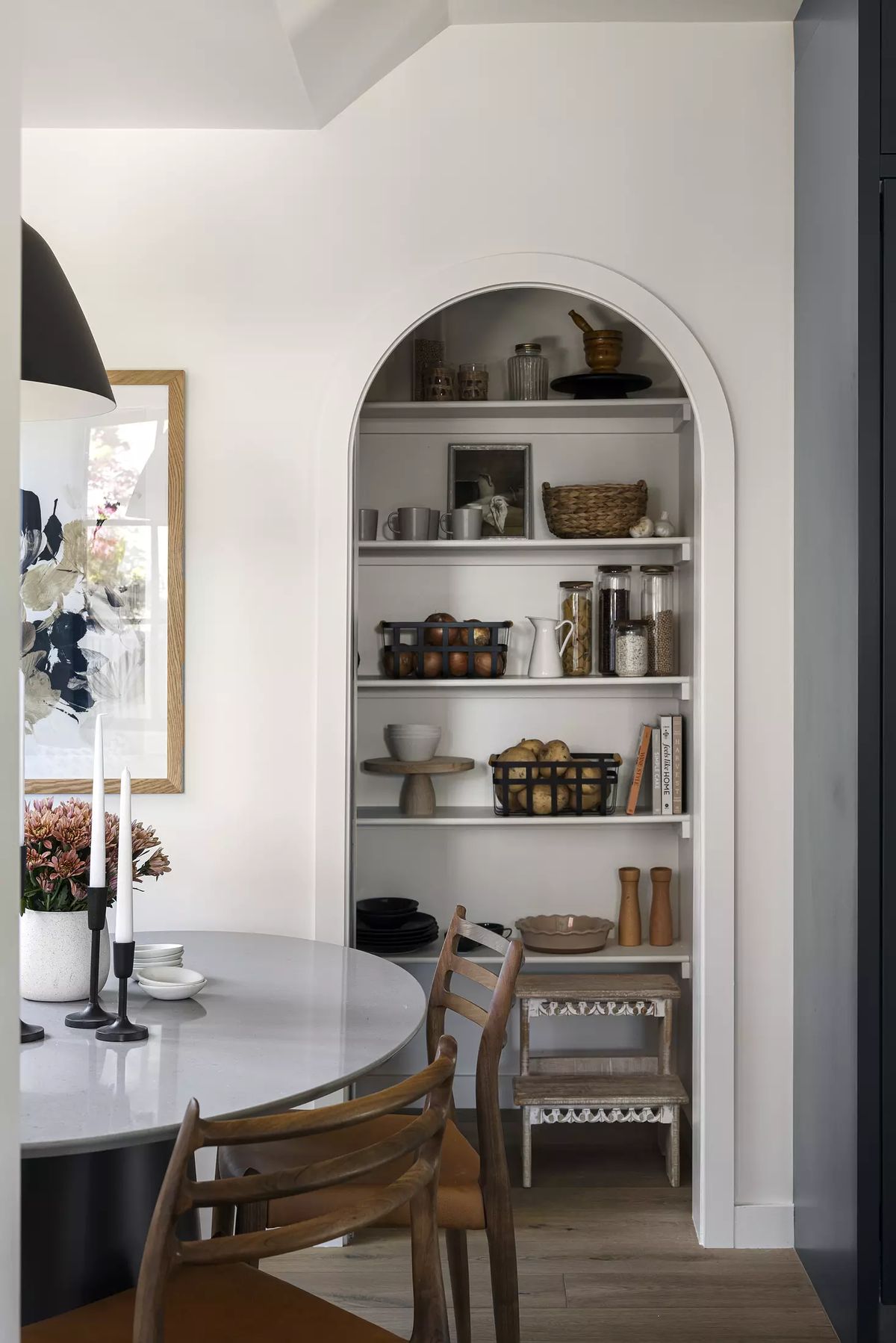 Kitchen featuring a round marble dining table, wooden chairs, and built-in arched shelving with kitchen items.