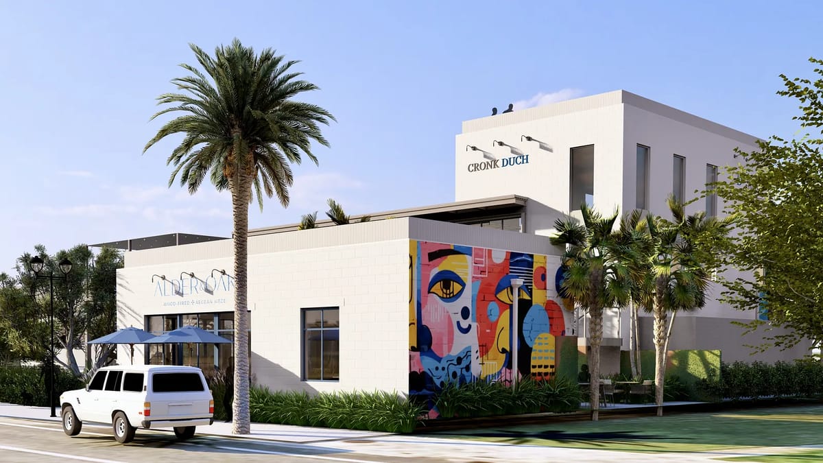 Exterior front view of a building with white facade, mural, palm trees, and parking area.