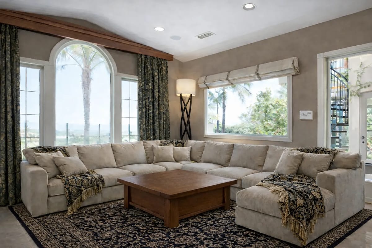 Living room with sectional sofa, wooden coffee table, area rug, large windows, and a floor lamp.