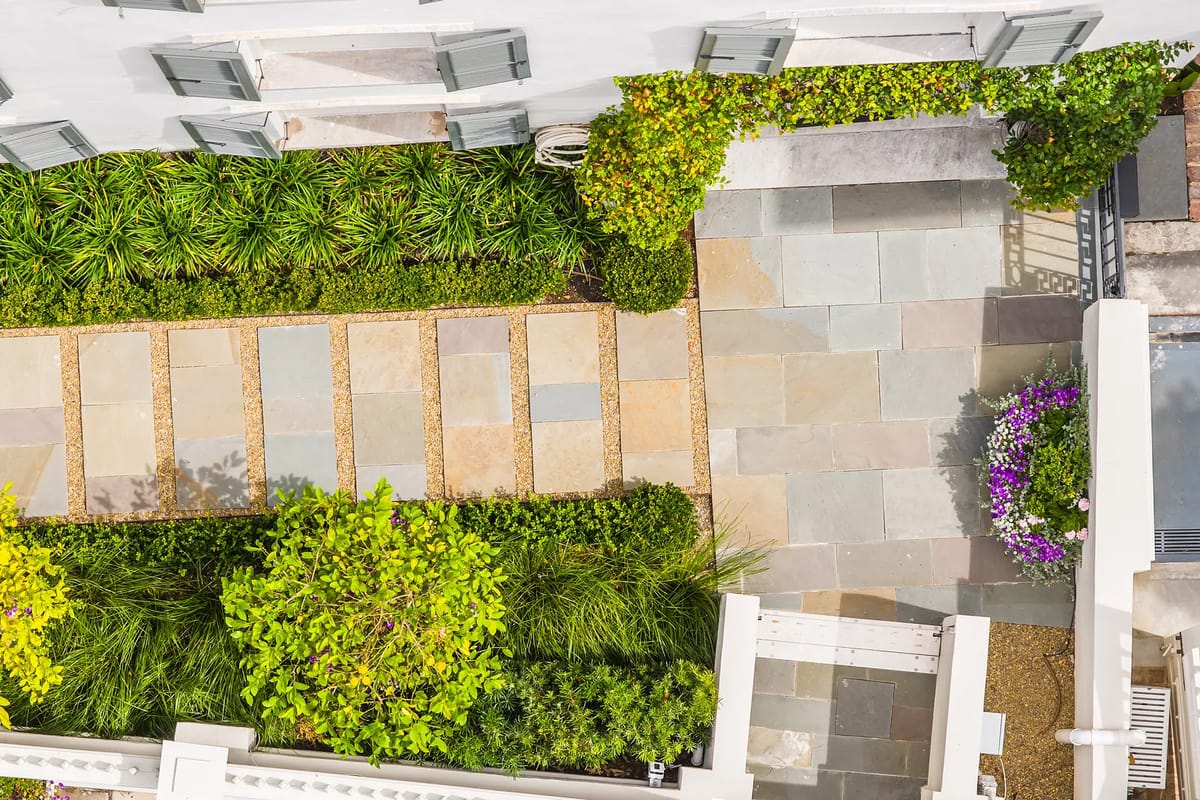 Garden with stone pathways, lush plants, and colorful floral arrangements.