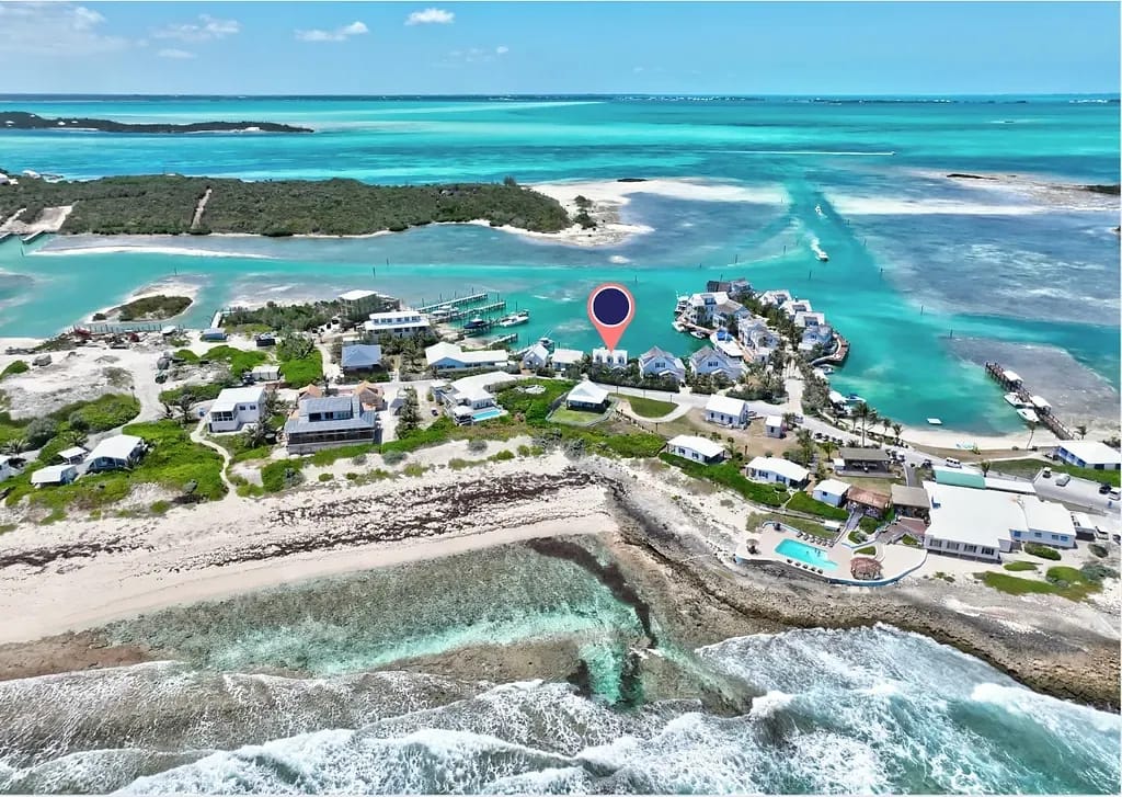Aerial view of a coastal area with buildings, turquoise water, and sandy shores.
