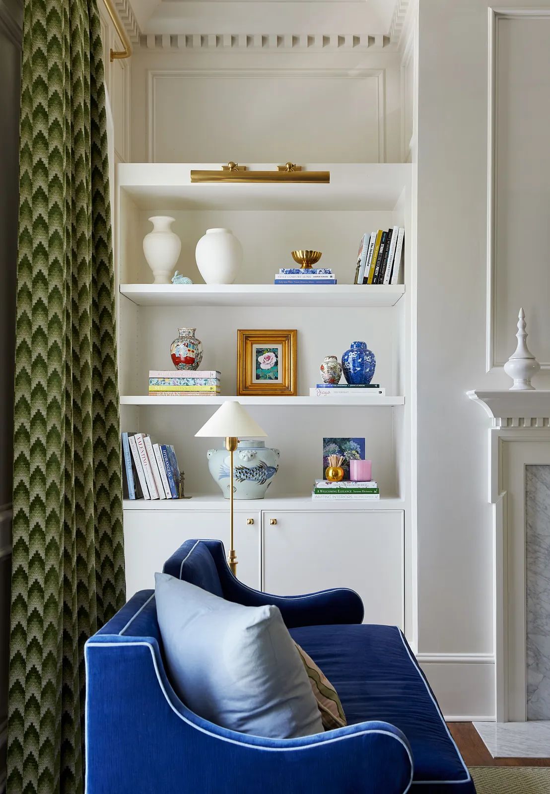Living room with blue sofa, built-in shelves, decorative items, and green curtain.
