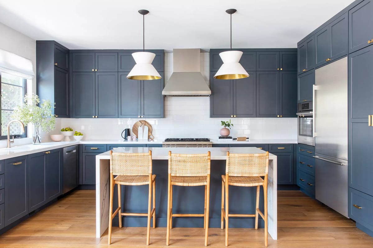 Kitchen with navy blue cabinets, white countertop, gas stove, built-in oven, bar stools, and pendant lights