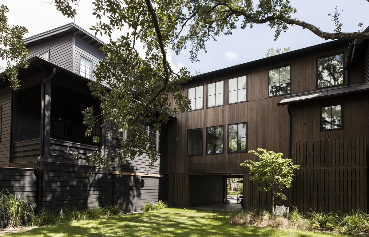 Exterior view with two wooden structures, grass, and shrubs.