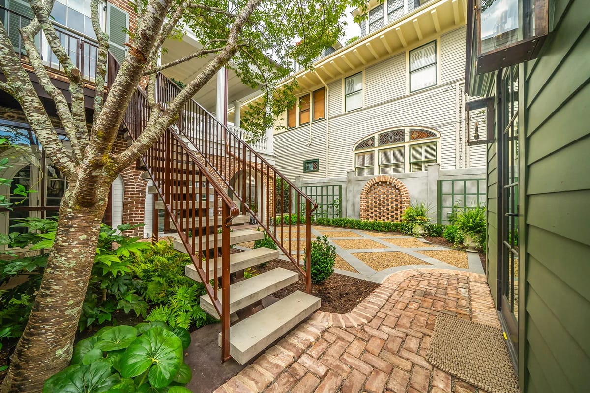 Outdoor garden area with wooden staircase, brick pathways, and various plants.