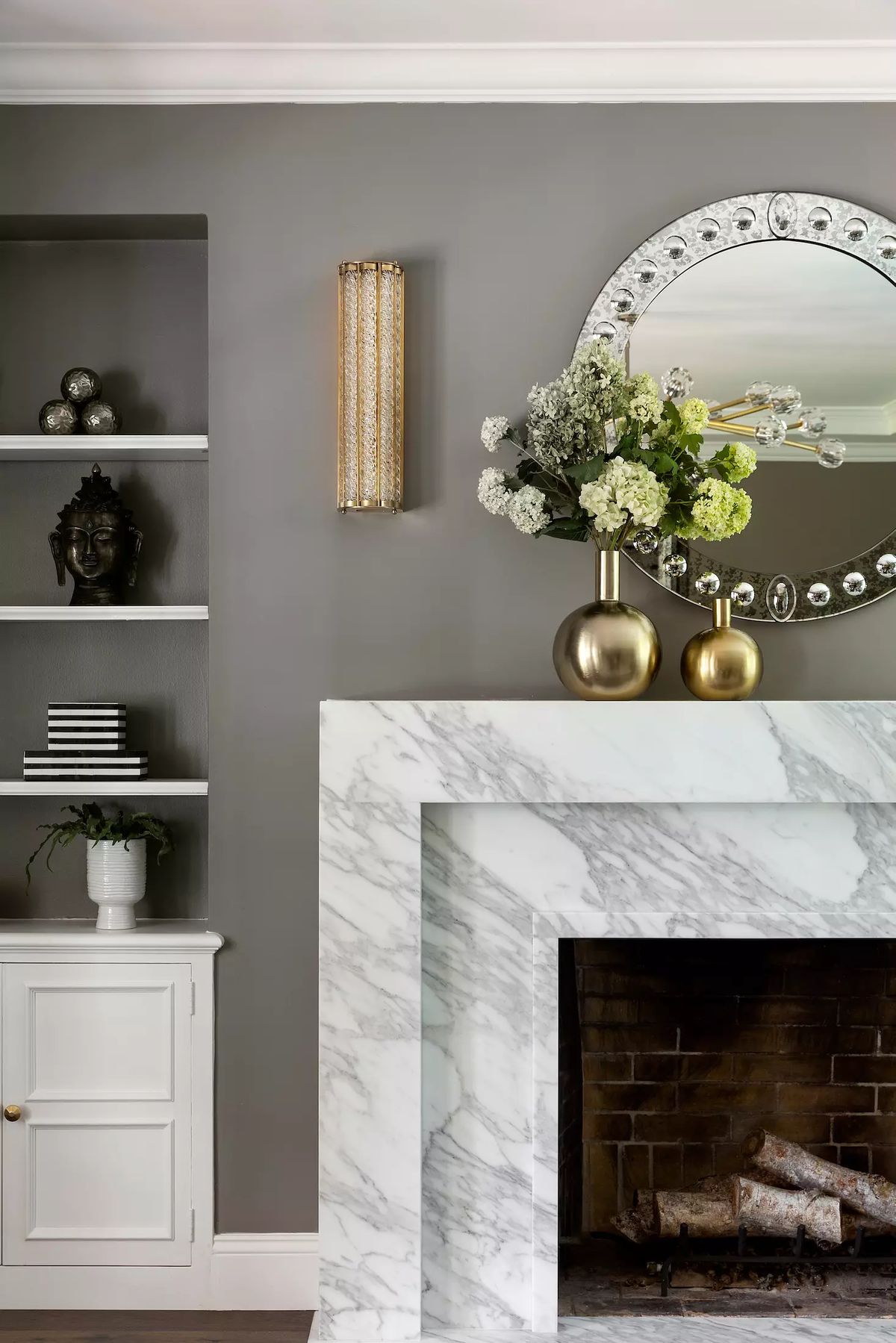 Living room with marble fireplace, decorative vases, built-in shelves, and white cabinet.