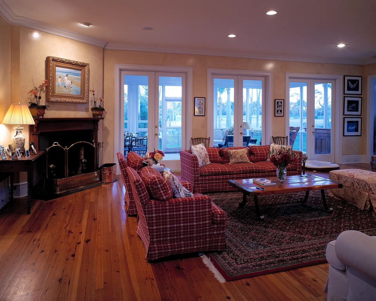 Living room with plaid sofas, coffee table, area rug, fireplace, and multiple doors to the outside.