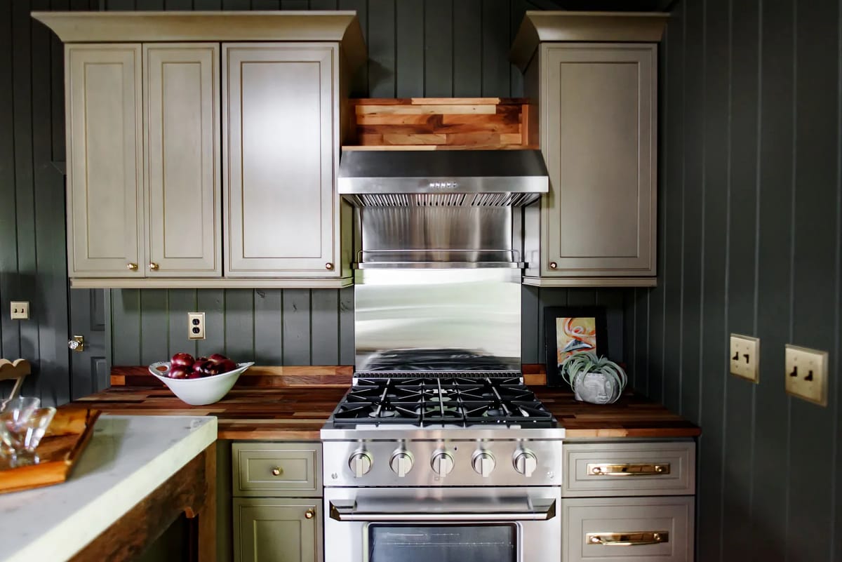 Kitchen with gray cabinetry, stainless steel range, wood countertops, and a bowl of red apples.