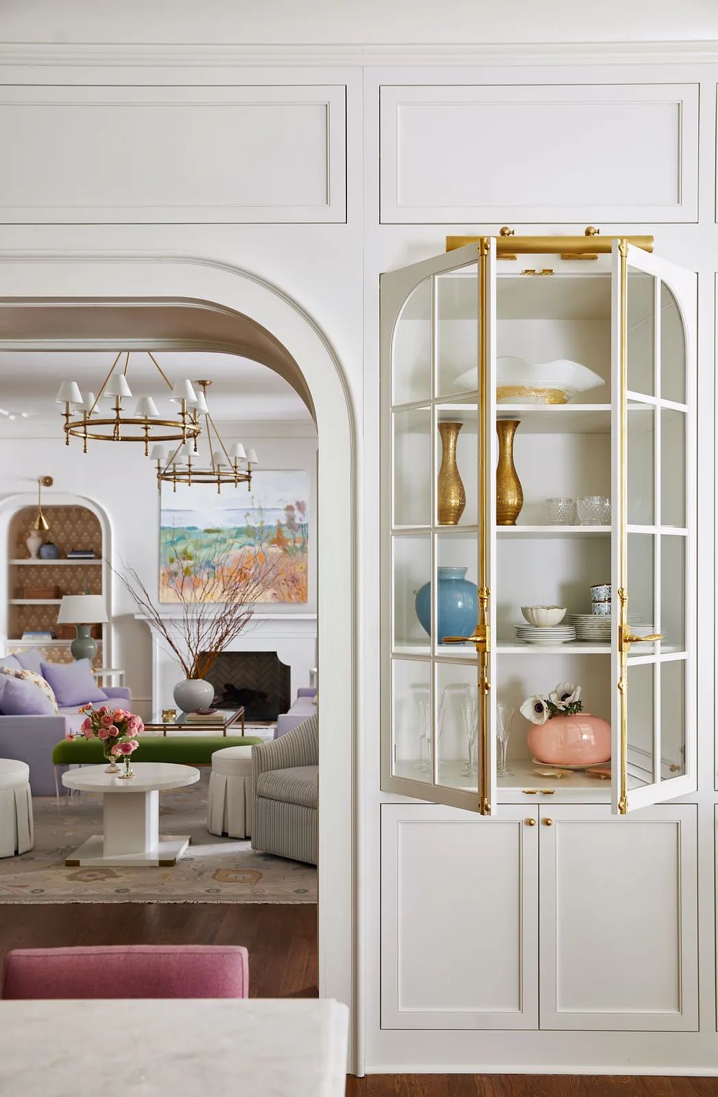 Butler's pantry with glass-front cabinets, decorative items, arched entryway, and wood flooring.