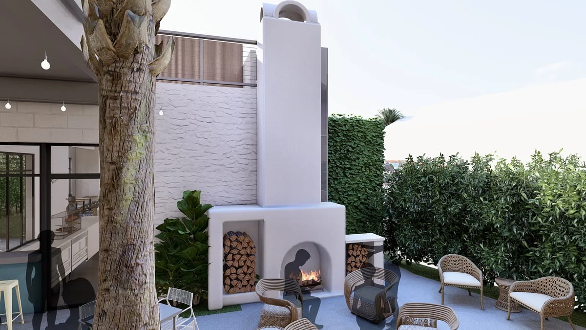 Patio with white outdoor fireplace, rattan chairs, stone floor, and greenery.