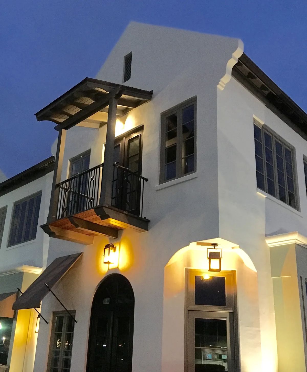 Exterior view of a two-story building with balcony, windows, and outdoor lighting.