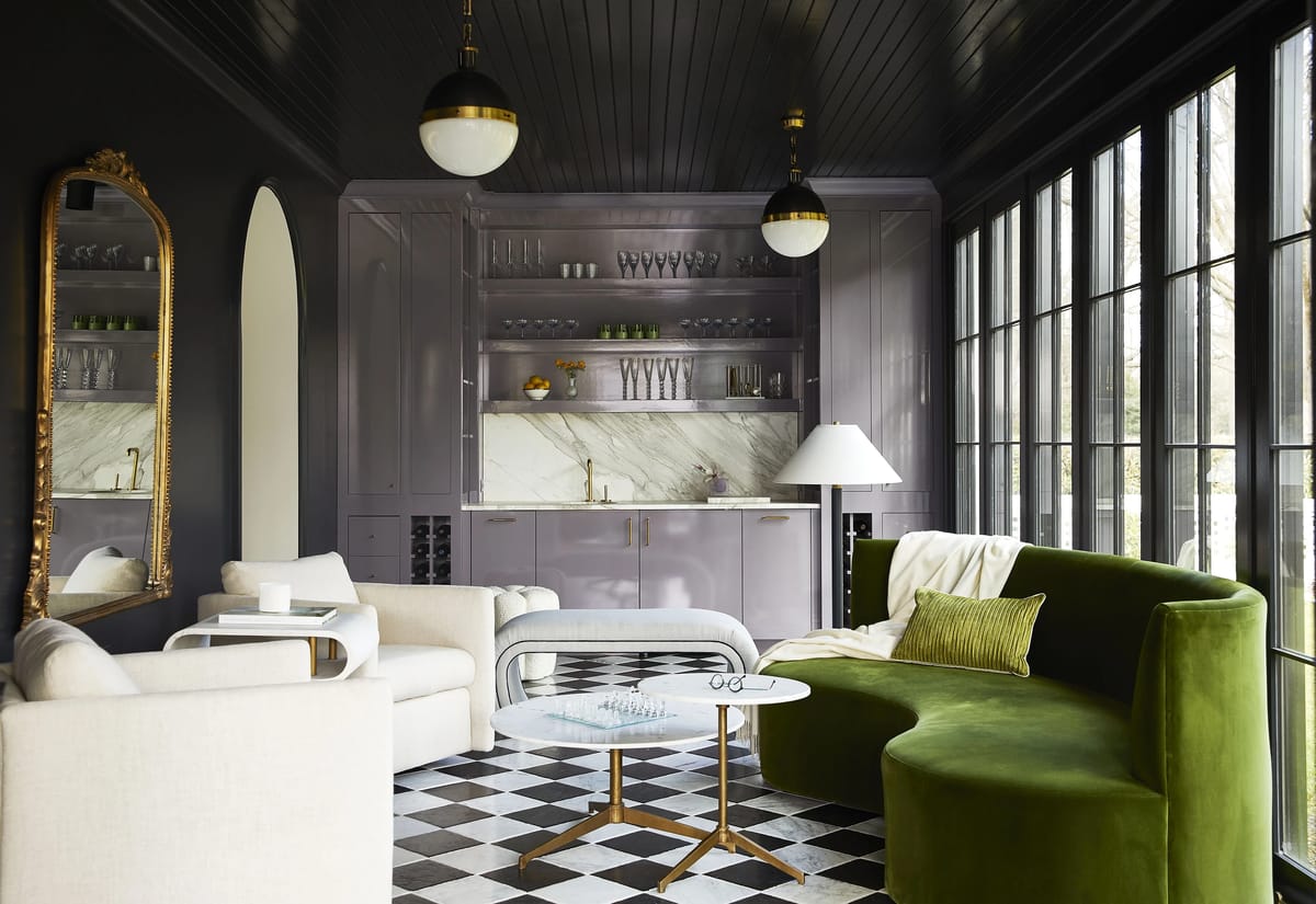 Living room with green curved sofa, white armchair, glass coffee table, and large windows.
