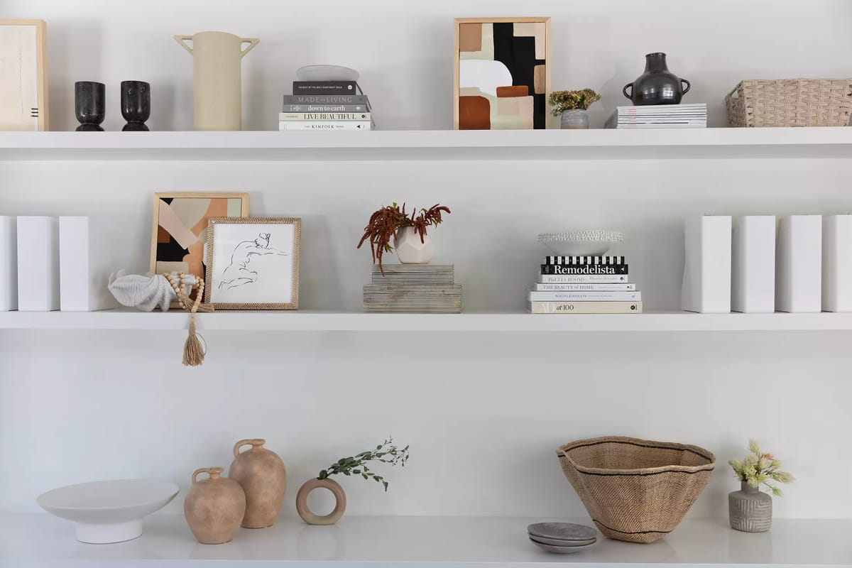 Decorative shelf unit with terracotta vases, woven basket, framed artwork, and books.
