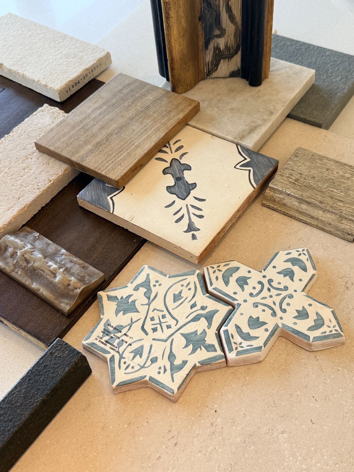 Collection of material samples including wood, tile, and stone on a light surface.