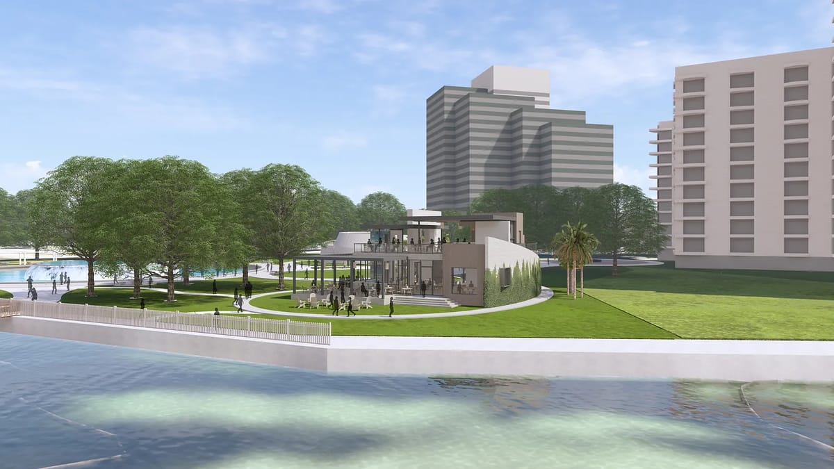 Modern building with glass windows, circular design, greenery, and palm trees in front of a body of water.