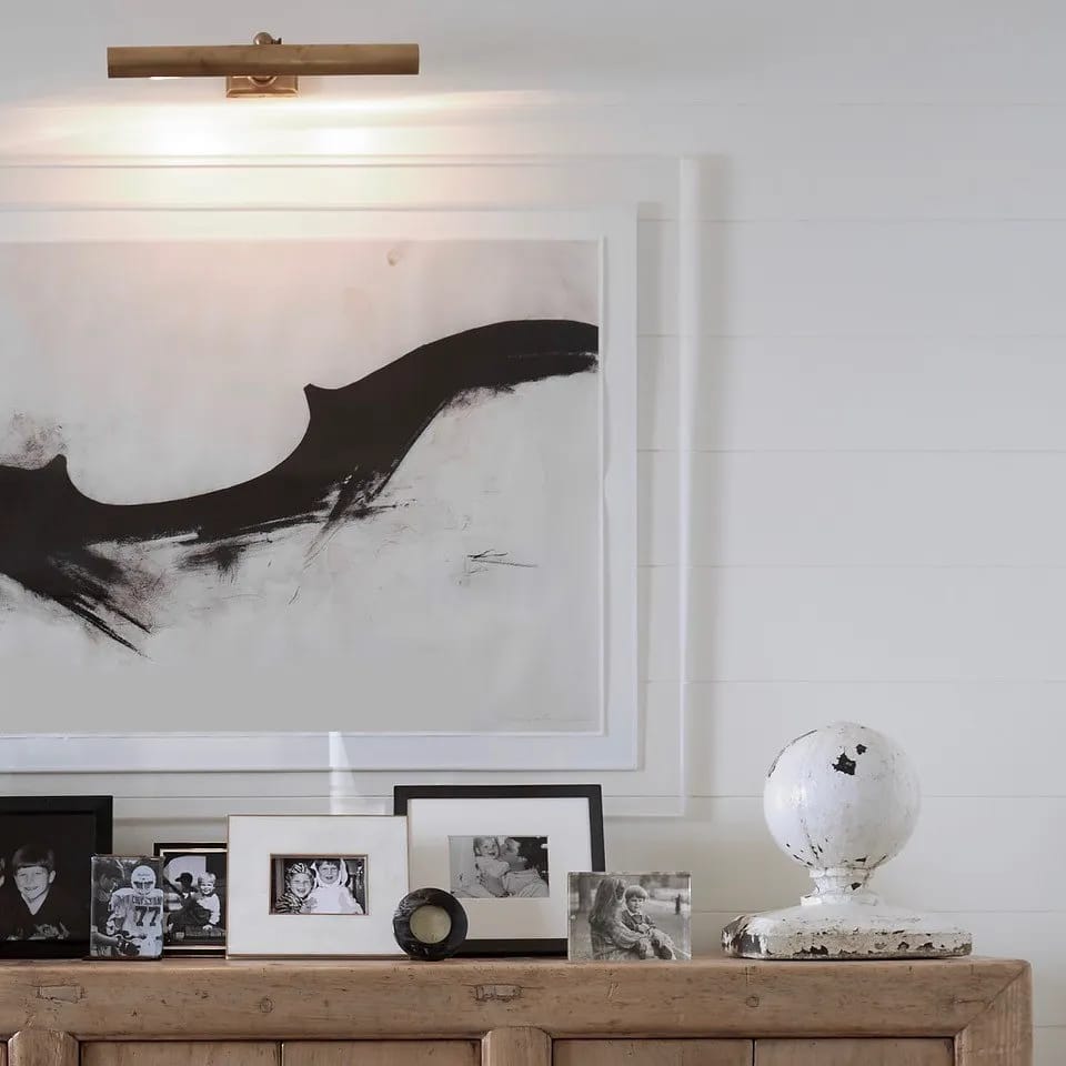 Wooden sideboard with framed photographs and decorative globe, featuring abstract artwork above.